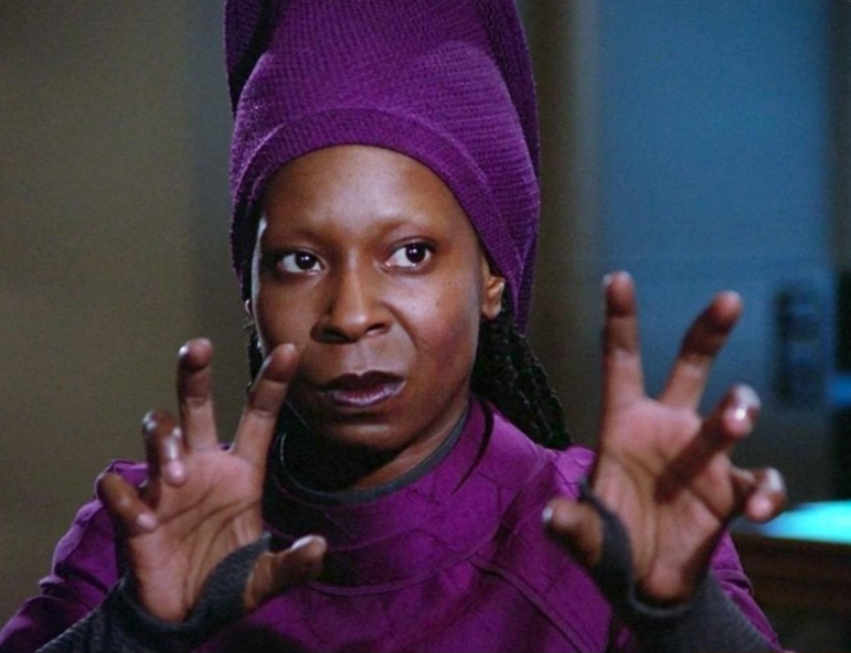 TNG Guinan with hands raised toward an off-screen Q